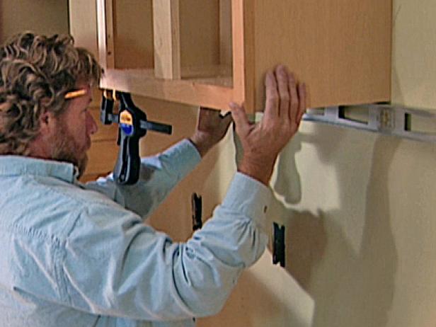 Once the second cabinet is adjusted so that it is perfectly level, the installers attach it to the wall using specialized wood screws.