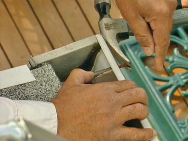 Position the 2' x 4' section in the gutter to brace against the force of the hammer, and pry out old gutter spikes one at a time.
