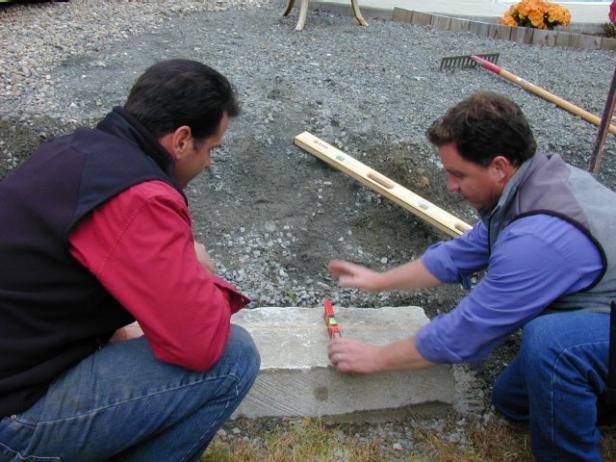 Place the first granite step onto the footer so that the front is flush with the wall face. The top of the step should pitch forward slightly so that water will run off. Check for level from side to side.