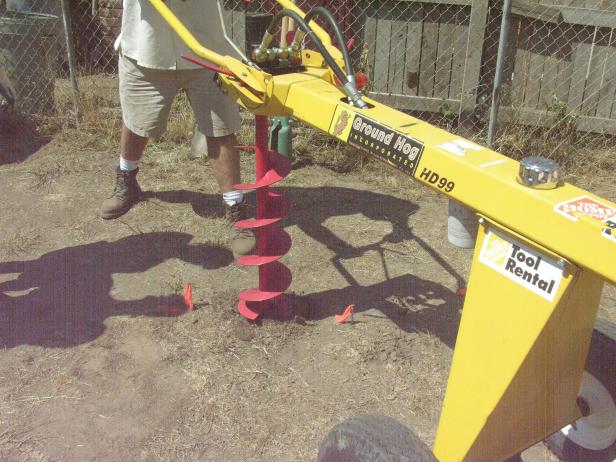 Temporarily remove the stakes and string and then use a power auger to quickly bore 15 inch holes at the marked locations.