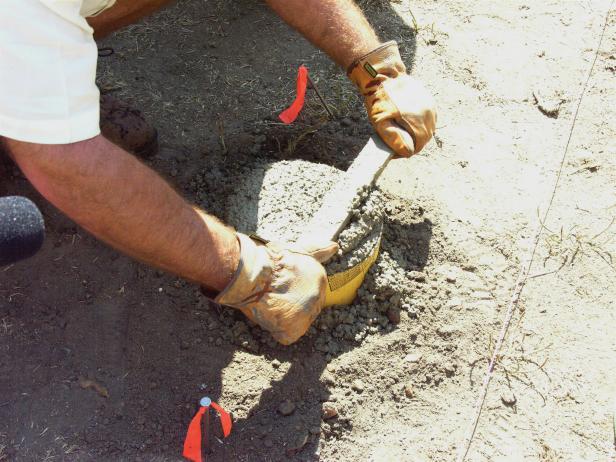 After mixing a batch of concrete, shovel it into the holes and lop off the excess using a spare wood stake.