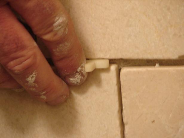 Check the level of each row before setting the next one, and use spacers to hold tiles in place while they dry.