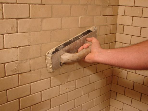 Use a rubber float to apply the grout. Start at the bottom and work up, keeping the float at an angle to the joints.