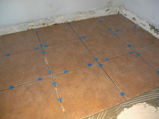 Lay the tiles down carefully and make any corrections and adjustments while the thinset is wet. Insert spacers to ensure each tile has the same size gap.