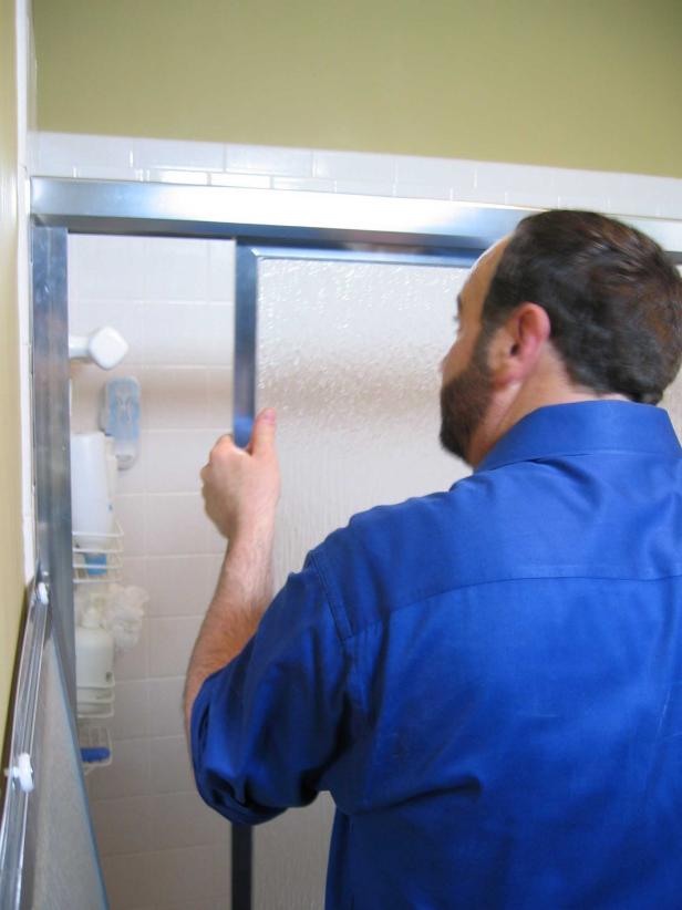 Hanging the doors is a two-step process. Standing on the outside of the tub, lift the inside panel with the rollers facing the shower and hang on the inner rail of the top track. Do the same for the outside panel, where the rollers now face away from the shower and the door will hang on the outer rail of the top track.