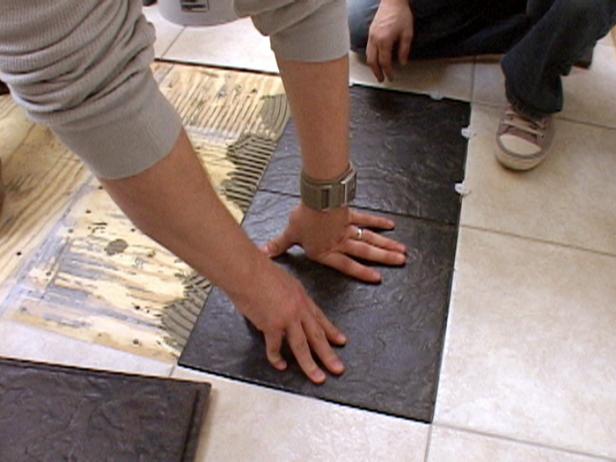 Close up of square black tiles being added to a spot in the bathroom floor - bathroom remodel on Bathtastic!DBTH-102