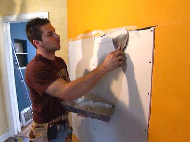 Contractor adds drywall mud to the new drywall that has been attached to the disaster house damage.