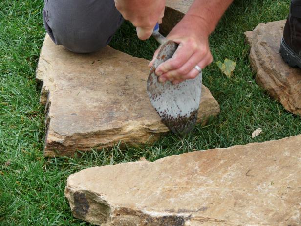 After laying out your walkway pattern, use a garden trowel or spade to cut through the turf around each stone.