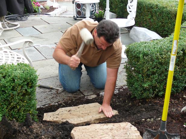 Use a rubber mallet to pound the stone into the gravel until its surface is flush with the surrounding sod surface. Use a level to make sure the individual stones are equal in height and level with the ground around them, and that none are set too high.