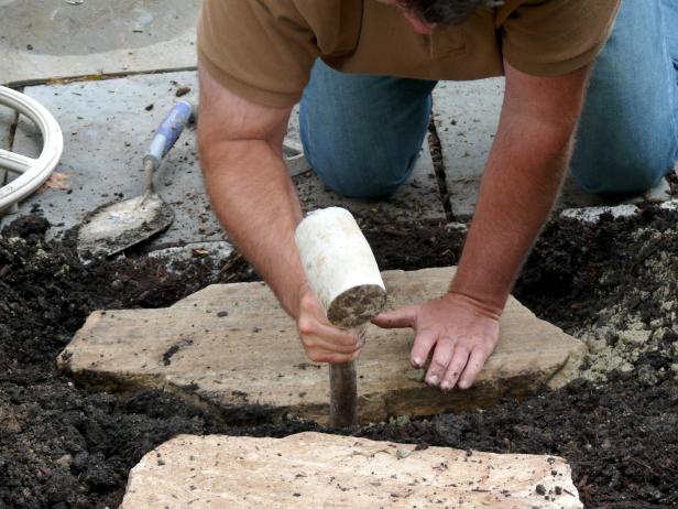 Check that none of your flagstones wobble. Add or remove gravel until each stone is level and is stabilized as you walk over it. Use a rubber mallet to help.