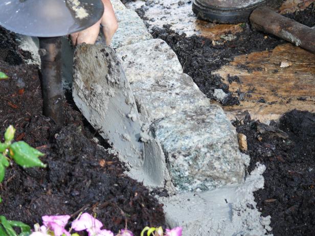To add strength to the border, place some mortar along the outer edges of the cobblestones below the path surface, and trowel it smooth at a slight angle away from the stone sides.