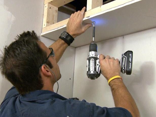 Man using a drill to install drywall on this home improvement project.