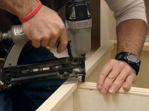 Using nail gun to attach the bookcase frame in this furniture construction project.