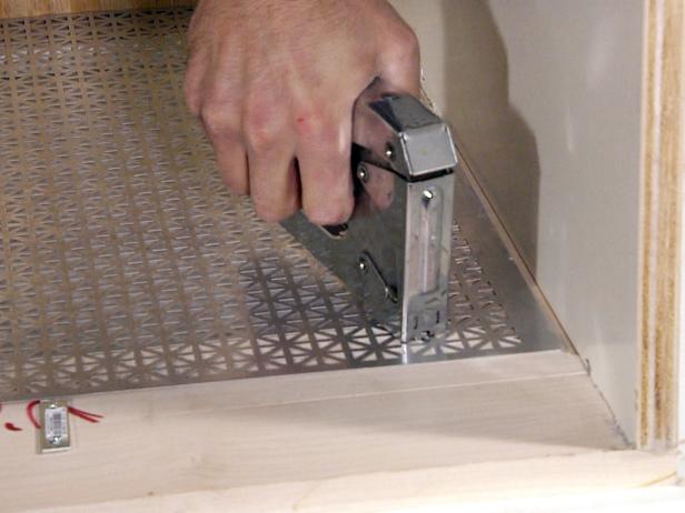 Using a stapler to attach the aluminum material to the wooden frame in this radiator project.