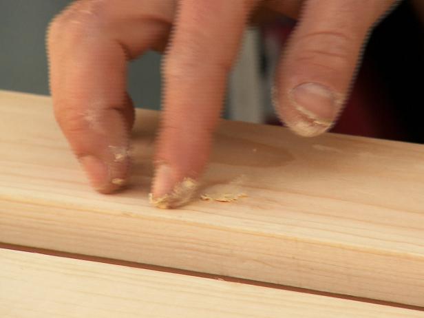 Close up of fingers putting wood filler into the spaces of the wood.