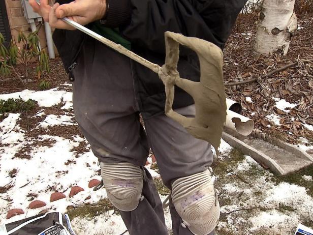 Man holds tool that mixes mortar solution when doing plank tile floor installation.