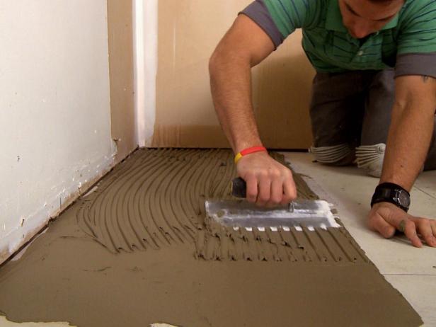 Spreading mortar on floor to add plank tile on this home improvement project.