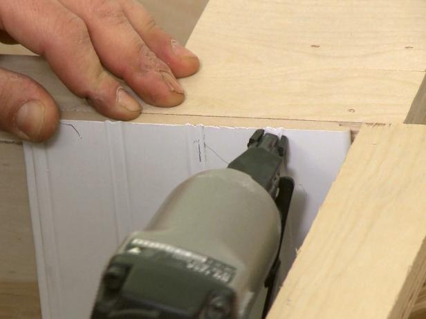 Close up of a nail gun being used to attach the wood together in this banquette wood project.
