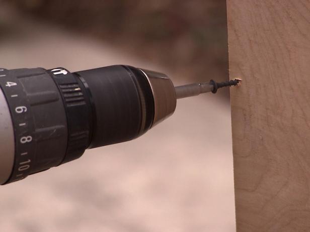 Drilling into banquette wood project with small screws and tool.