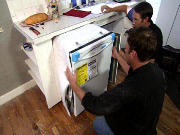 Josh Temple, host of Disaster House, watches as the dishwasher gets intalled into the kitchen area.