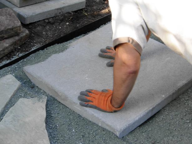 Using the edging as your guide for height and as a starting point, choose a piece of flagstone or a concrete paver with a straight edge. Slide the piece back and forth, working it into the base below until it sits flush with the border and level to the eye.