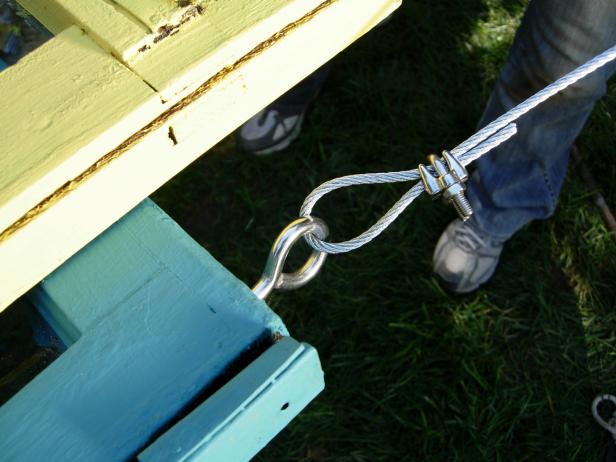 Close up of a hook and cable being used to hang colorful windows in this outdoor room design on Yard Crashers.