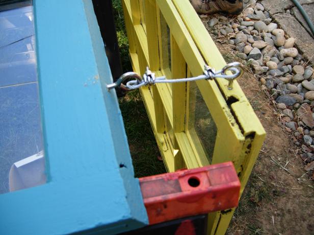 Close up of blue and yellow windows bineg hung outside the back yard of this outdoor room design on Yard Crashers.