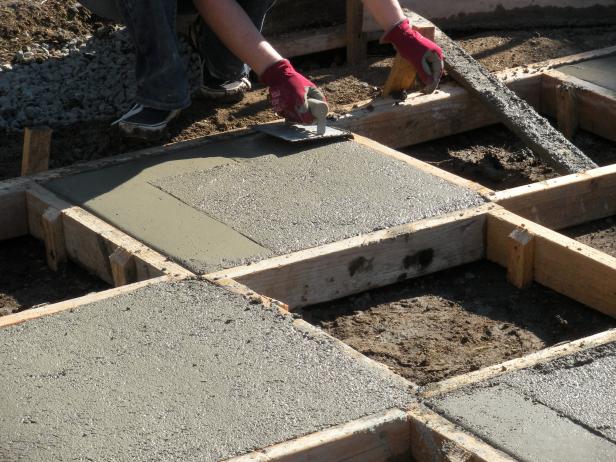 Pour concrete into the squares that don't have stakes in the middle of them. The concrete will go in the open areas between the square frames so they measure exactly 2' x 2'. Once the squares are poured, trowel the top until it's smooth. Add a powder color hardener over the top if you would like a pop of color and trowel it in until it's incorporated.