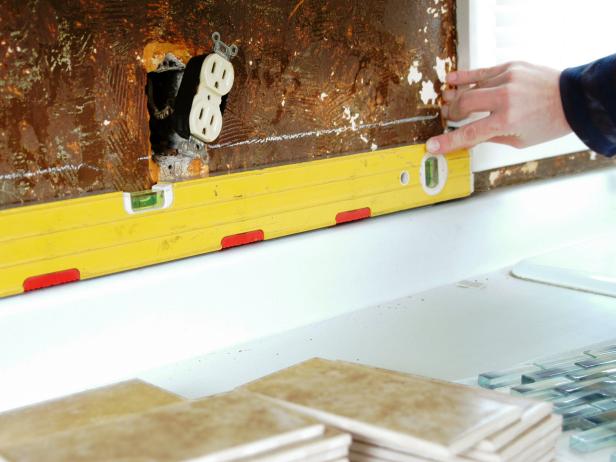 Check that the countertop is level. If it is not, stand a tile at the lowest spot and mark a level line on the wall at the tile’s top — this will be your starting point. Use a standard level or laser level to extend this reference line across the wall and around the entire area that is being tiled