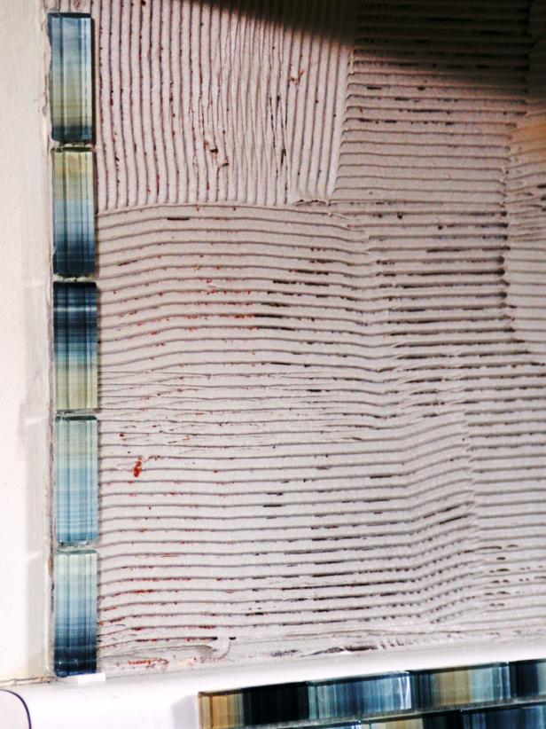 If you have a vertical border row, start there and remember to put a spacer at the bottom to allow room for caulking. Press the tiles firmly into place, placing spacers between each tile if required.