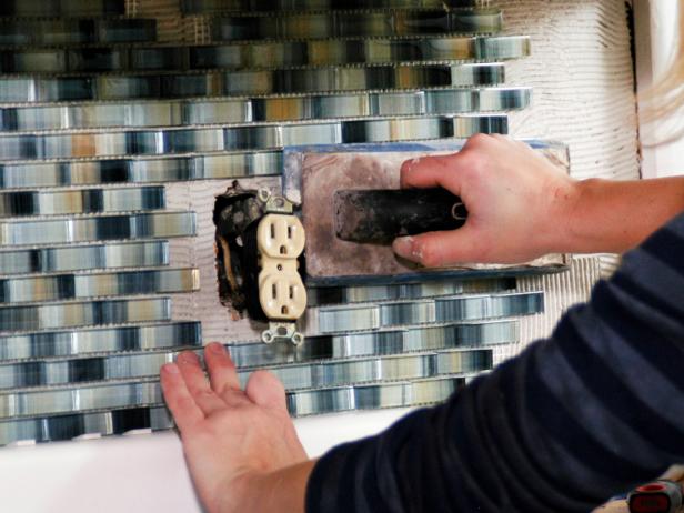 Use a utility knife to cut the sheet of tile to size. Press it firmly with your hands then use a clean grout float to tamp it onto the adhesive.