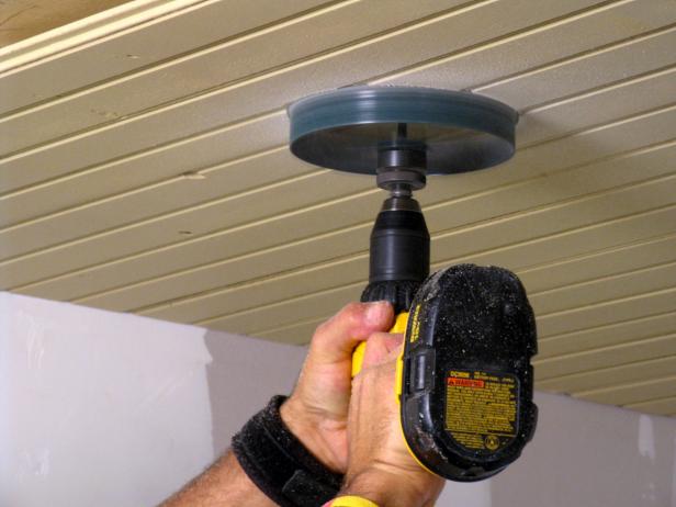 Tool cuts through wooden ceiling planks to make a round hole.