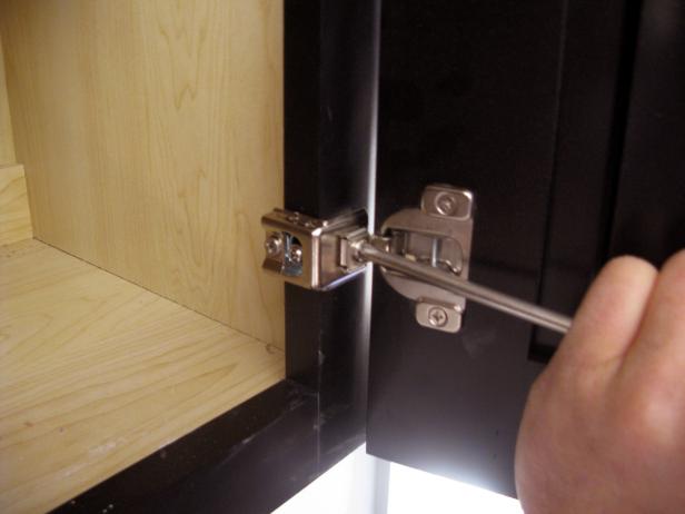 Using a screw driver to install cabinet doors.