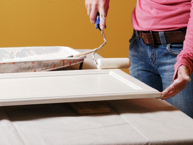 Amy paints the edges of the cabinet door with a second coat of paint.