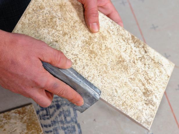 Sanding a piece of tile on its edge.