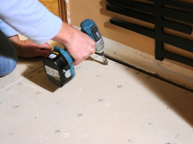 Josh uses a drill to attach the cement board.