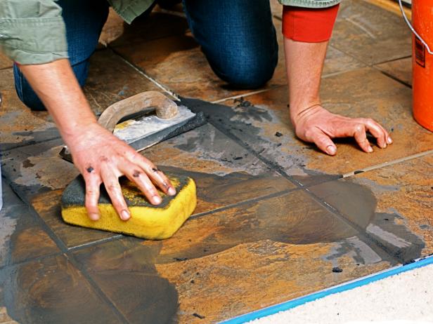 Josh gets on his knees to wipe off the mixture on the floor tile.