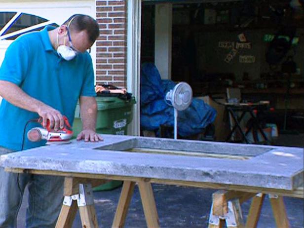 Wearing a respirator, use a sander to smooth the concrete countertop. You'll need to work progressively from 100-grit sandpaper, finishing with 220-grit.