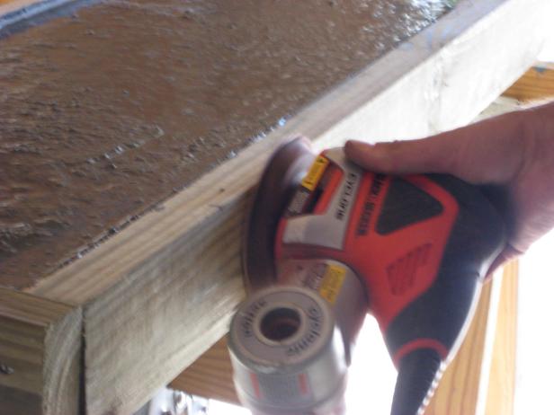 Run an orbital sander (without sandpaper) along the sides of the frame, to vibrate bubbles out of the concrete.