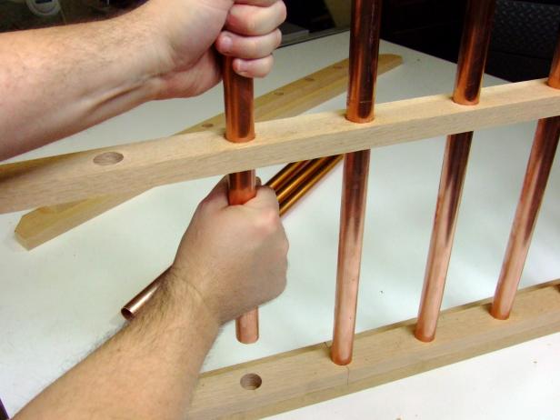 The next step to assembling your base is inserting the copper pipe parts through the holes in the support rails attached to the assembly. A good tip to help ease the pipe through the holes is to apply liquid soap or paste wax inside the holes.
