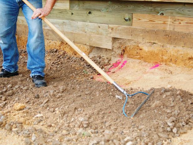 Fill the excavation with compactable gravel, to a depth of five inches, tamping it down as you go. Rake the top surface smooth and level with a steel rake