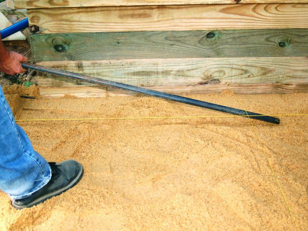 Spread the sand over the gravel base to a depth of one inch. Screed the sand with a 2x4 using a pair of 1-inch PVC pipe and a depth guide.