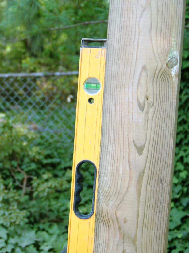 Once the post holes are dug, set the posts. Place the 6x6 post into the hole. Remember to check that the post is plumb using a three foot level, as you go.