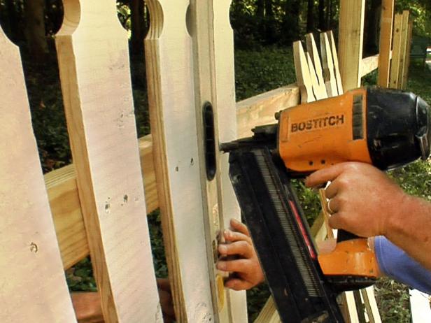 Lay a leveled 2x4 on the ground below the rail to use as a base for maintaining a consistent height of 2 inches from the ground. Evenly spacing the pickets as you go, attach them to the rail using a nail gun