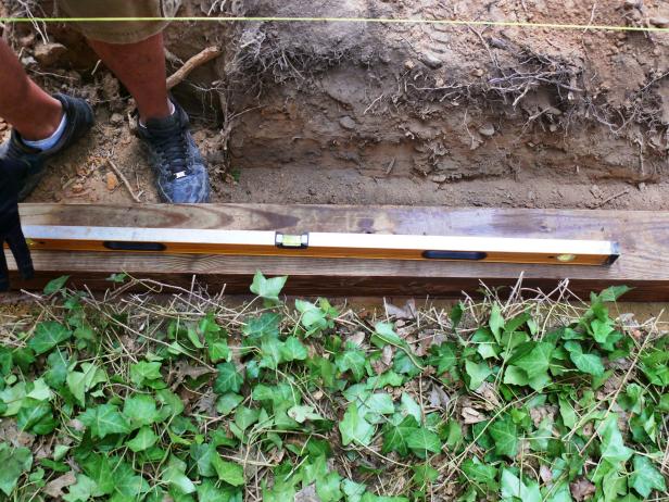 With the trench dug and leveled- you're ready to install the foundation row of timbers.