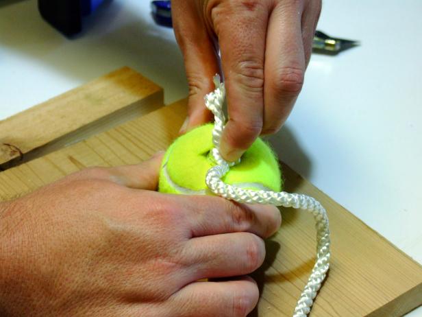 Push each knotted end into the slit in the tennis balls. Make sure the knot is completed inserted and tug slightly to pull the knot tight against the inside of the ball.