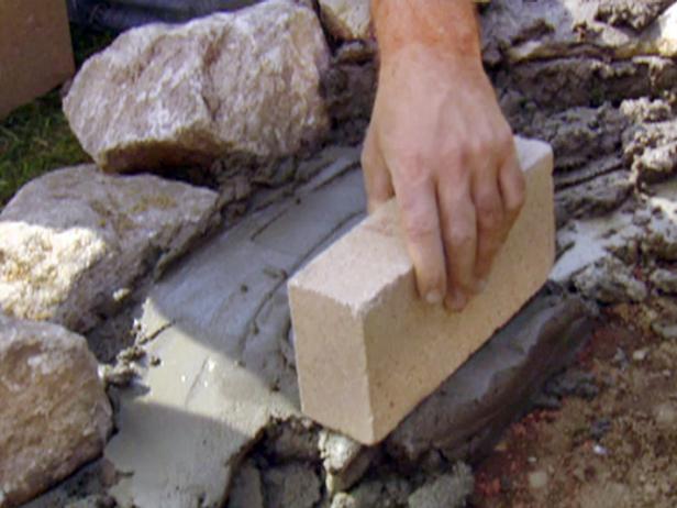 As the first few levels of stones begin to take shape along the outside edge of the fire pit, begin to lay fire bricks to form the inner wall of the structure.