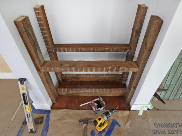 Measure the inside dimensions between the legs so when the reclaimed wood shelves are cut, they will sit atop the braces. The front part of the shelves should be flush with the front legs and back wall. Screw or nail the two shelves into place. The tops of these shelves will be visible when the bar door is swung open; therefore, use old, rusty nails or finish nail.s