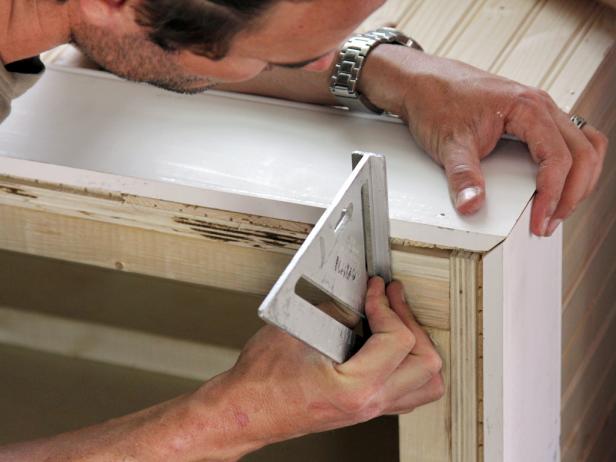 With the bench on its back, use a speed square to align the bottom of the baseboard and corners.