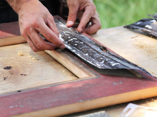 Apply heavy-duty construction adhesive to the recessed portion of the frame, being careful not to drip adhesive onto the stained face of the frame. Insert the cut stamped tin. Use small finishing nails and a nail set to secure the tin in place